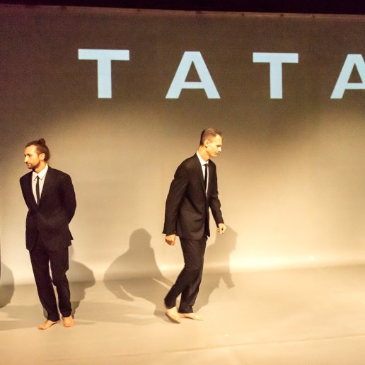 Spektakl Tata. Trzej młodzi mężczyźni w garniturach. Napis TATA.