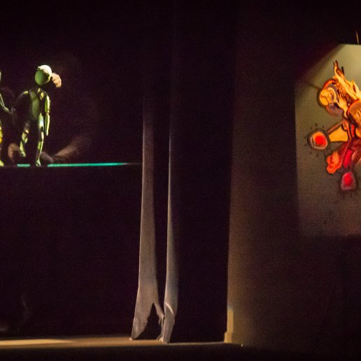 Spektakl "Blaski i cienie". Dwie lalki idą po linie. Obraz malowany przez malarkę na żywo podczas spektaklu.