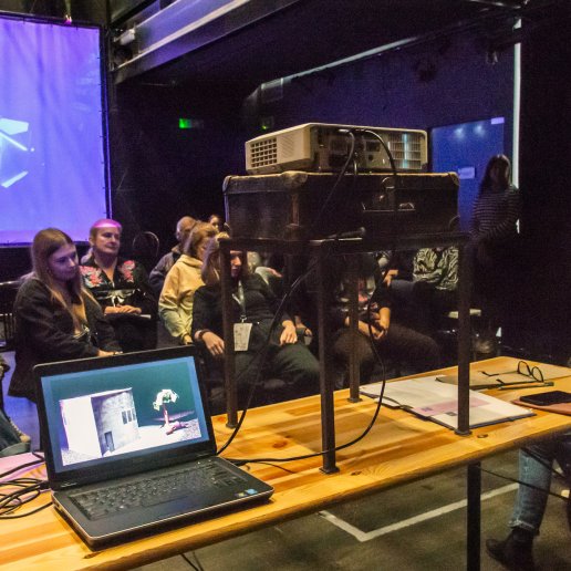 Filmowanie formy - spotkanie dotyczące animacji poklatkowych stworzonych przez studentów wydziału reżyserii teatrów lalek we Wrocławiu. Do laptopa podłączony jest projektor, wyświetla film. Publiczność wydarzenia.