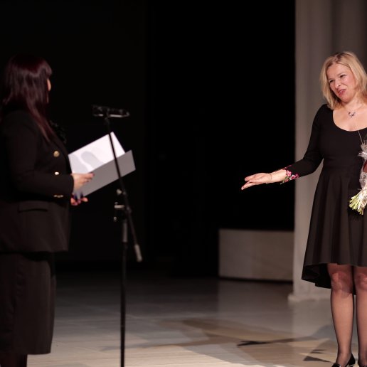 Agnieszka stoi na scenie wraz z Naczelniczką Wydziału Kultury Magdaleną Matyjaszek, która trzyma otwarty list gratulacyjny.