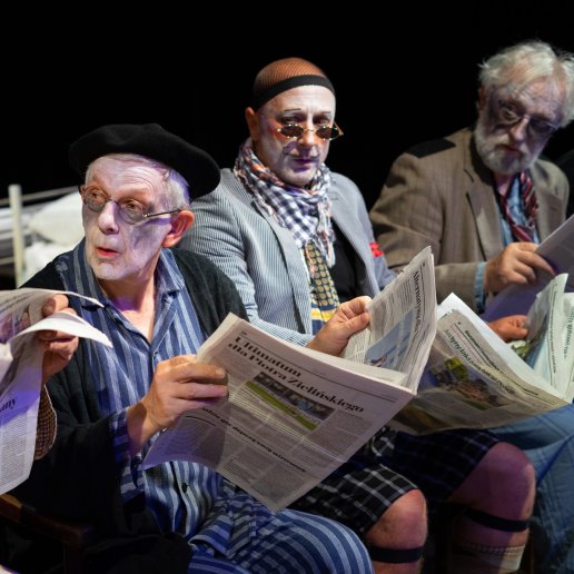 Czworo aktorów seniorów. Wszyscy siedzą w rzędzie, trzymają otwarte gazety.