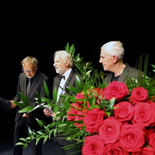 Wiceprezydent Opola Przemysław Zych gratuluje jubilatom. Na pierwszym planie ogromny bukiet czerwonych róż.