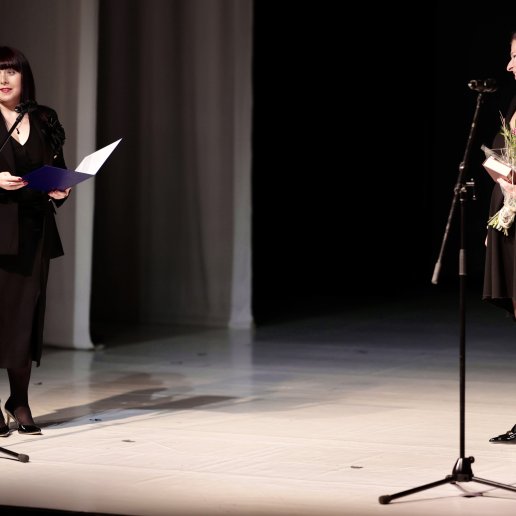 Agnieszka stoi na scenie wraz z Naczelniczką Wydziału Kultury Magdaleną Matyjaszek, która trzyma otwarty list gratulacyjny.