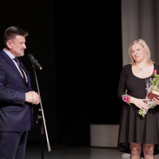 Agnieszka stoi na scenie wraz z Wicewojewodą Opolskim Piotrem Pośpiechem, który mówi do mikrofonu.